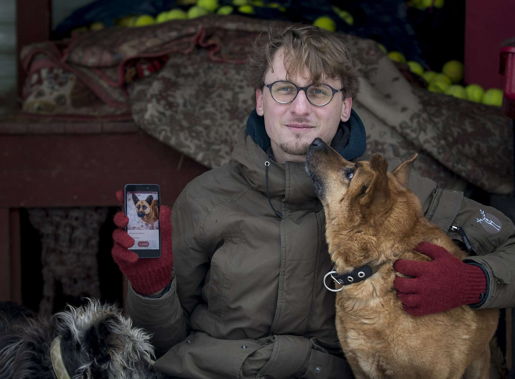 En esta foto Vaidas Gecevicius, quien desarrolló una aplicación que ayuda a hacer coincidir perros callejeros con dueños potenciales, posa para una foto con un perro y muestra el perfil de este perro en la aplicación en Vilnius, Lituania. AP