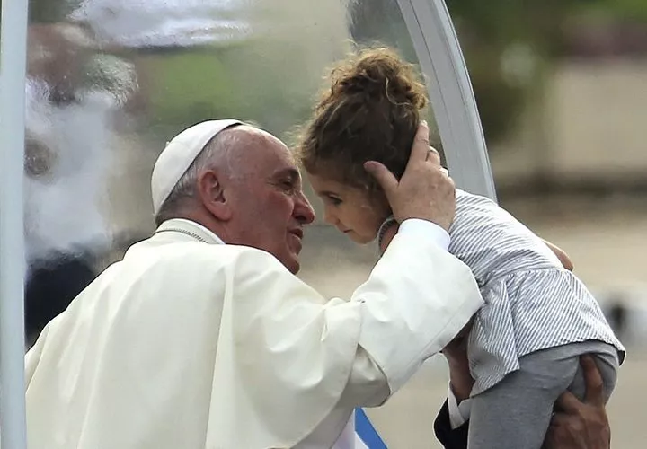 El Papa  besa a una niña a la que hiceron llegar al papamóvil. EFE