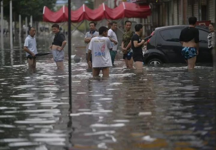 Fotografía que muestra a varias personas caminando por una carretera inundada en Shenyang, provincia de Liaoning, al nordeste de China.  /  Foto: EFE