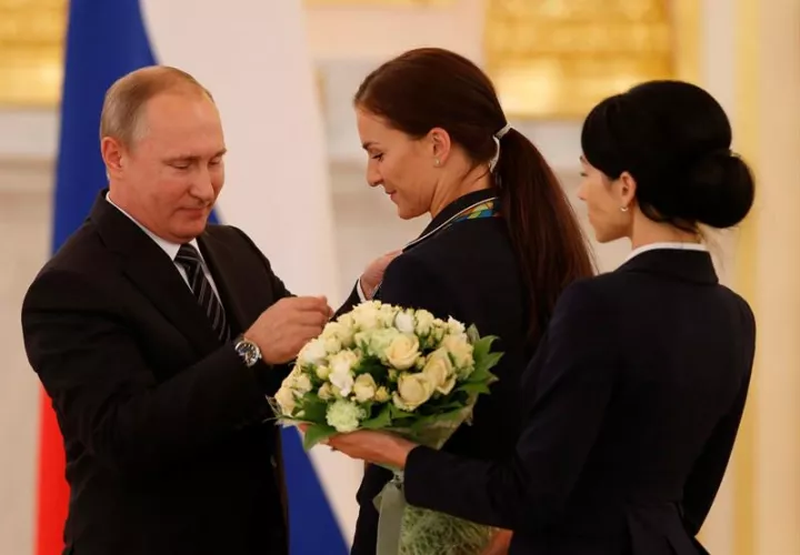El mandatario de Rusia, Vladímir Putin (izq), impone una insignia a la campeona olímpica de esgrima, Sofia Velikaya (c). Foto EFE 
