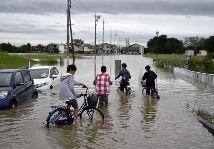 Niños circulan con sus bicicletas por una calle inundada en Tokio.  /  Foto: EFE Archivo