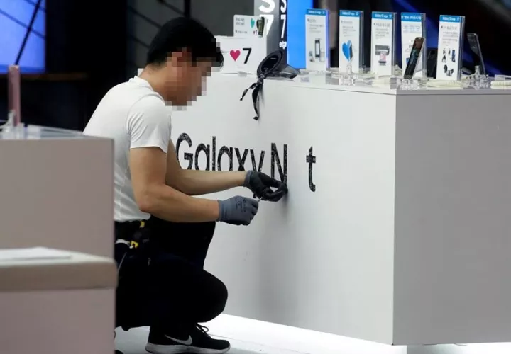 En la imagen, un empleado quitando las marca publicitaria de Galaxy Note 7 de la empresa Samsung Electronic en una tienda en Seúl (Corea del Sur). EFE/Archivo