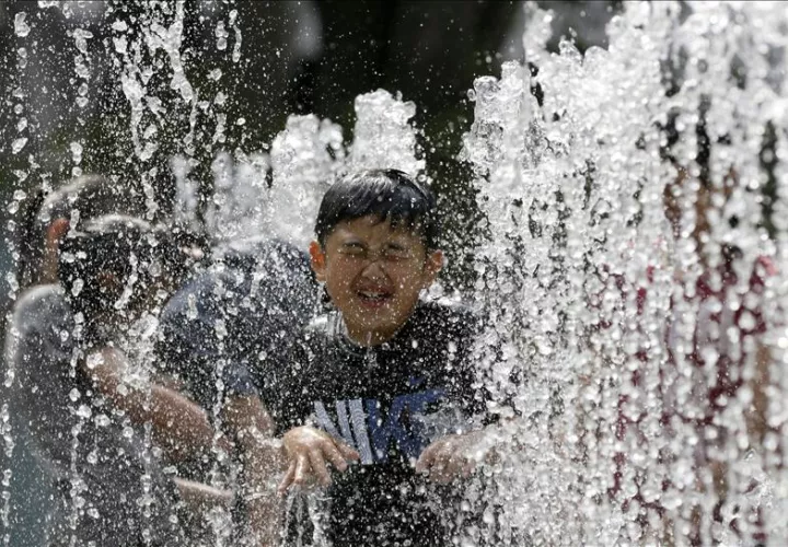 Varios niños juegan en una fuente para refrescarse en Tokio (Japón). EFE/Archivo