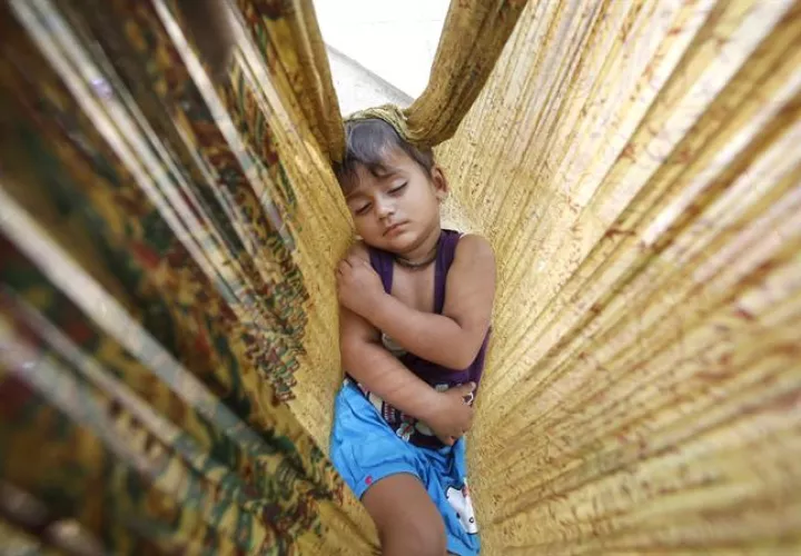 Un niño duerme en una hamaca de tela en una carretera de Nueva Delhi, India. EFE/Archivo