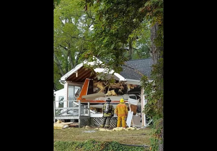 Los bomberos inspeccionan los restos de un pequeño avión después de chocar contra una casa en Middlesex.  /  AP