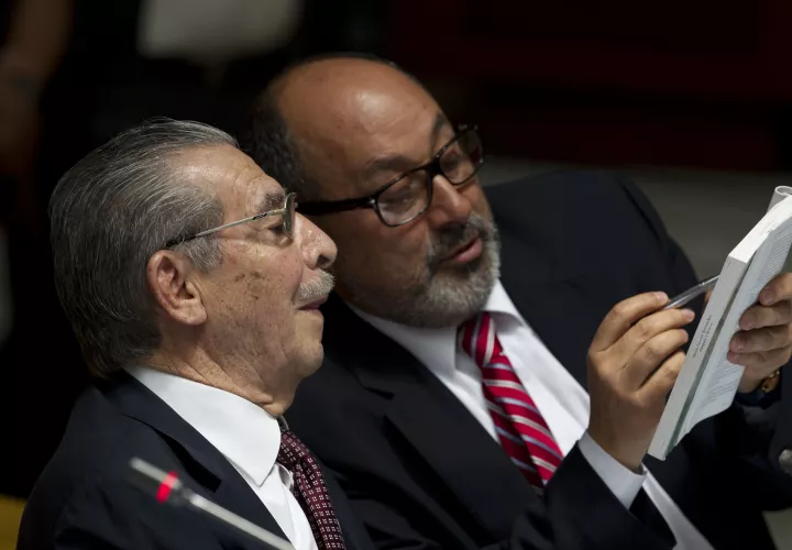 El exdictador de Guatemala, José Efraín Ríos Montt, se fue, habla con su abogado Moises Galindo durante su juicio por cargos de genocidio en la ciudad de Guatemala. AP