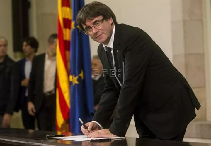 El presidente de la Generalitat, Carles Puigdemont, firma el documento después de comparecer ante el pleno del Parlament para trasladar los resultados de la jornada del 1-O. EFE