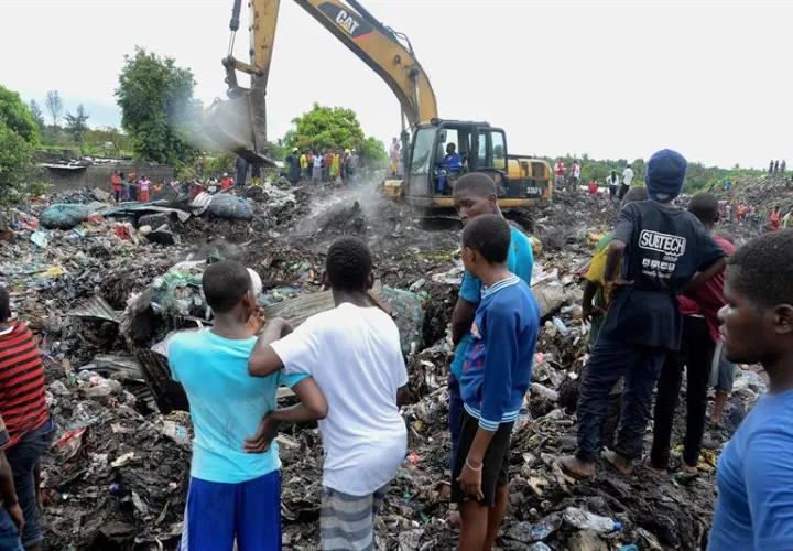 Varias personas observan las labores de búsqueda de los servicios de emergencia en un basurero de Maputo (Mozambique) este 19 de febrero. EFE