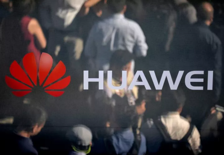 Un grupo de visitantes se reflejan en un espejo con el logo de la compañia de telefonía móvil Huawei. EFEArchivo