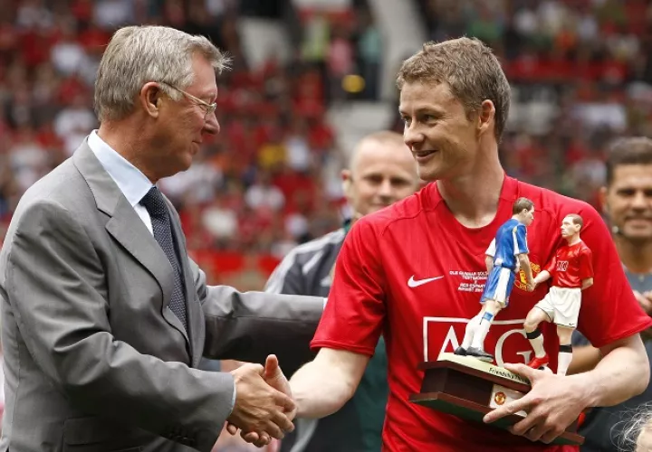 El noruego Ole Gunnar Solskjaer (rojo) estrecha la mano de su extécnico en el Manchester United, Sir Alex Ferguson. /AP