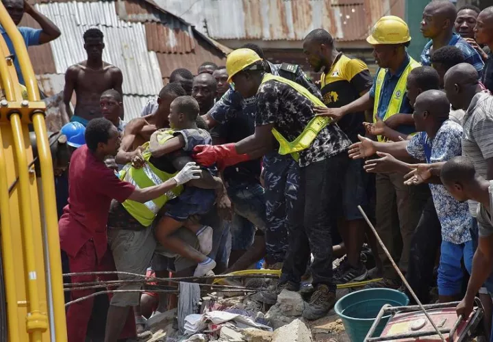 Operarios rescatan a un niño entre los escombros tras derrumbarse un edificio este miércoles en Lagos, Nigeria. EFE