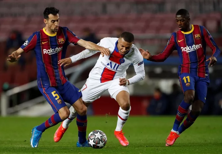Busquets (i) y Dembélé (d) disputan un balón ante Mbappé (c)./EFE