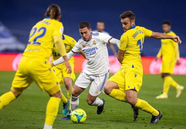 El delantero del Real Madrid, Eden Hazard (c), intenta llevarse el balón ante el defensa del Cádiz, Juan Cala.