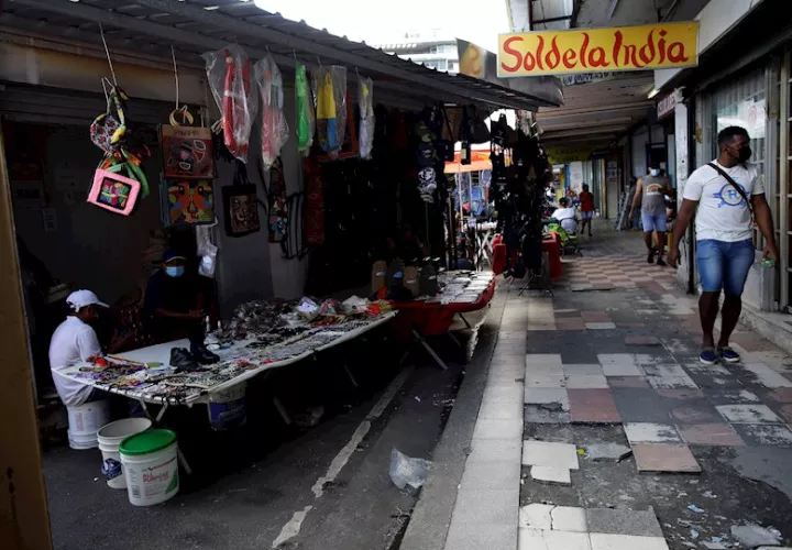Varias personas caminan frente a un puesto de buhonería durante la pandemia de la covid-19 en la Avenida Central, en Ciudad de Panamá. EFE