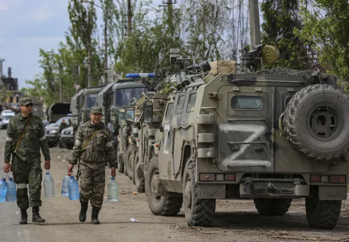 Milicianos de la autoproclamada República Popular de Donetsk (RPD) llevan botellas de agua mientras se prepara la evacuación de los militares ucranianos de la planta siderúrgica Azovstal sitiada en Mariupol, Ucrania.