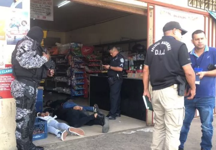Los tres asaltantes tirados en el piso del comercio.