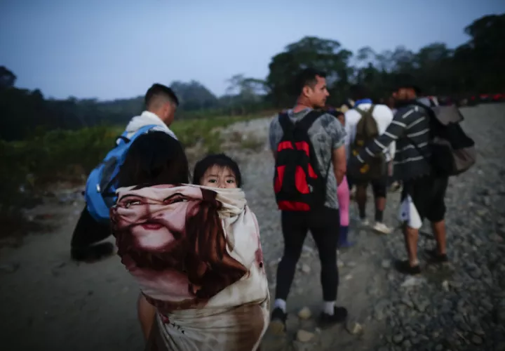Adultos y niños migrantes hacen fila en la comunidad de Bajo Chiquito para ser trasladados a la Estación de Recepción Migratoria (ERM) de San Vicente, en Metetí (Panamá).EFE