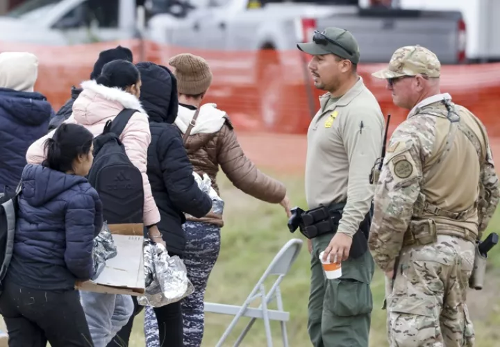 Un grupo de migrantes (i) que pasa junto a agentes de la Patrulla Fronteriza (c) y de la Guardia Nacional de Texas (d), en Shelby Park en Eagle Pass, Texas (EE.UU.). EFE / Archivo