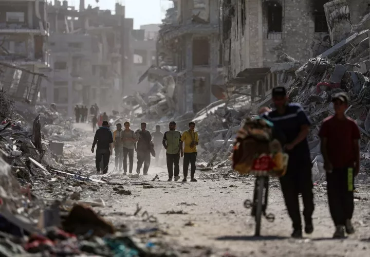 Palestinos caminan entre los escombros.