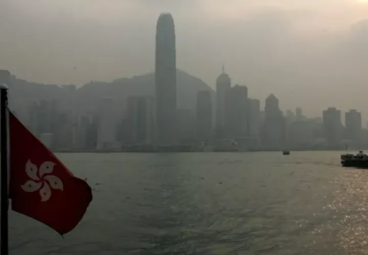 Una bandera de la región de Hong Kong ondea mientras al fondo un transbordador navega por el puerto de Hong Kong. Foto: EFE