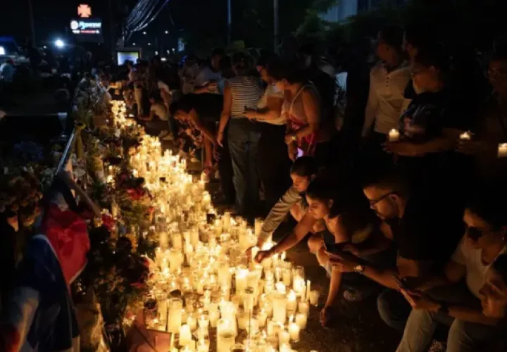 Fotografía de personas prendiendo velas en homenaje a los fallecidos en la discoteca Jet Set.  Foto: EFE