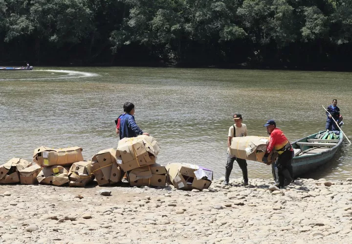 Personas descargan mercancía proveniente de Ecuador, en el cruce irregular sobre el río San Miguel que conecta a San Miguel (Colombia) con la zona rural de Lago Agrio (Ecuador). Foto. EFE