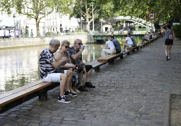 Varias personas descansan a orillas del Sena en París, luego de una de las madrugadas más calurosas. Foto. EFE
