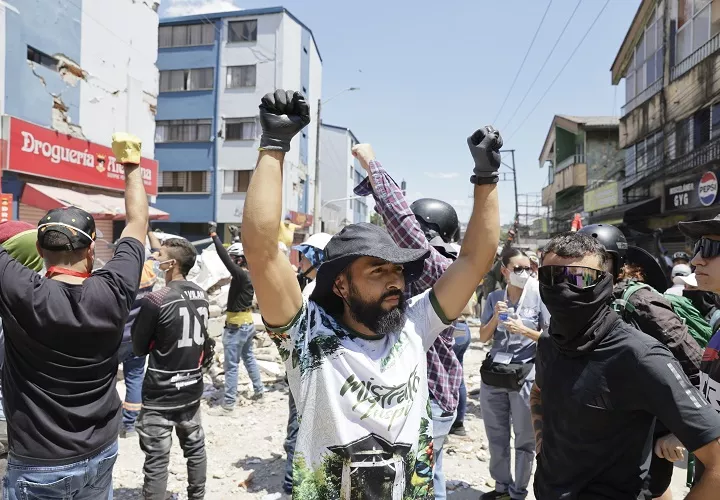 Rescatistas y voluntarios levantan los brazos pidiendo silencio durante una operación de rescate en los escombros de un edificio en el sector de La Lorena en Pereira, Colombia. Foto. EFE 