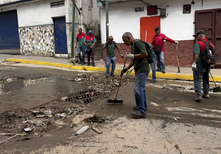 Un grupo de personas fue captado limpiando una calle, tras las fuertes lluvias de este fin de semana en Caracas (Venezuela). Foto. EFE