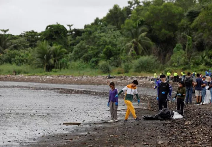 Personas recogen basura durante una jornada de limpieza de playas este sábado, en la desembocadura del Río Juan Díaz. Foto: EFE